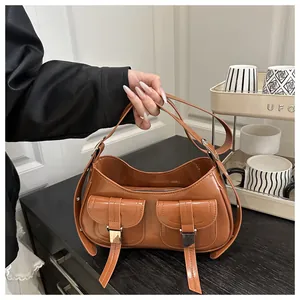 Detail of caramel glossy hobo bag featuring silver metal buckles and polished leather texture