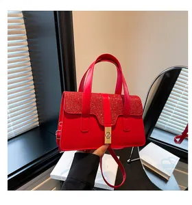 Detail of red glitter handbag featuring a gold twist lock and a sleek leather finish
