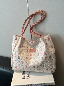 White cartoon print tote bag with pink rope handles leaning against a gray wall