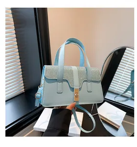 Detail of light blue handbag featuring a rhinestone flap, twist lock, and top handle
