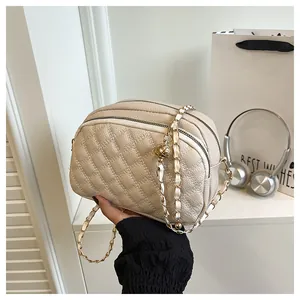 Dettaglio borsa trapuntata beige con catena dorata e fibbia a sfera regolabile