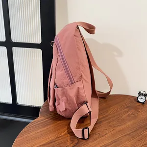 Dettaglio dello zaino in nylon rosa con tasca laterale e tracolla regolabile