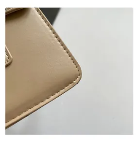 Close-up of fine leather texture and neat stitching on a beige crossbody handbag