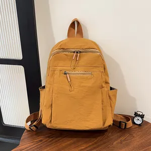Dettaglio zaino in nylon giallo con doppie tasche frontali con zip su tavolo in legno