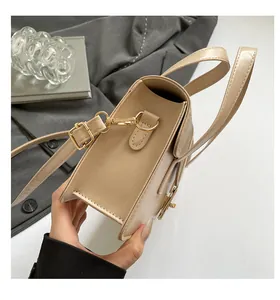 Detail view of beige crossbody bag with matte faux leather and gold hardware