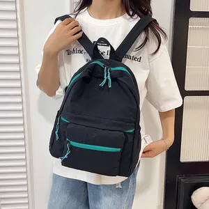 Detail of black nylon backpack featuring contrast green zippers and blue knotted pullers