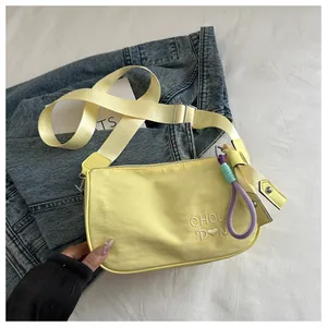 Detail van lichtgele crossbodytas met wit borduursel en een geweven koordkwastje