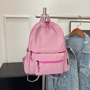 Detail of pink nylon backpack with decorative zipper pulls and branded side label