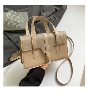 Detail of beige textured handbag with gold glitter flap and metal twist-lock buckle