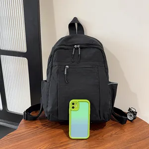 Dettaglio di uno zaino in nylon nero minimalista con tasca a zip su piano in legno