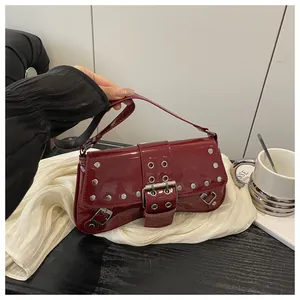 Dettaglio della borsa a tracolla in vernice bordeaux con borchie argentate e hardware Y2K