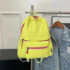Close-up of lightweight neon yellow nylon backpack with pink zippers and side brand label