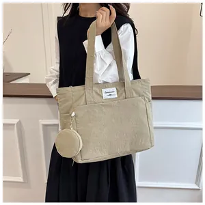 Macro detail of khaki nylon tote bag featuring front pocket and round coin purse attachment