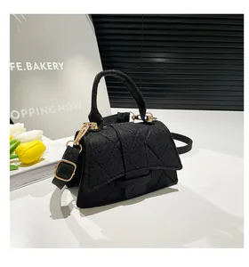 Detail of black felt crossbody bag with diamond quilting and gold metal hardware