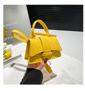 Detail of yellow felt handbag with diamond quilting and top handle for women