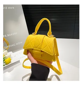 Close-up of a bright yellow felt mini bag featuring classic quilted rhombus stitching patterns