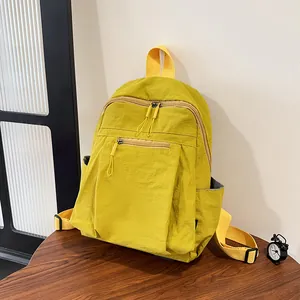 Dettaglio dello zaino in nylon giallo con doppie cerniere e pratiche tasche laterali