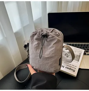 Detail of grey waterproof nylon crossbody bag with drawstring closure and fashion label