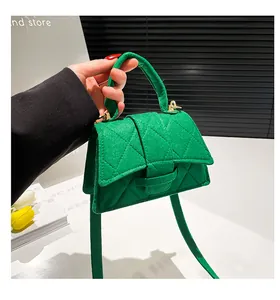 Detail of green felt mini bag featuring diamond quilting and gold hardware accents