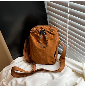 Close-up of brown waterproof nylon crossbody bag with pleated texture and drawstring pocket