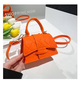 Close-up of orange quilted felt handbag with rhombic patterns and mirror reflection