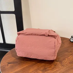 Dettaglio del tessuto in nylon stropicciato rosa polvere e base capiente dello zaino
