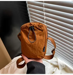Close-up of caramel nylon waterproof crossbody bag featuring drawstring and black zipper