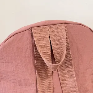Dettaglio dello zaino in nylon rosa con maniglia superiore e cuciture della tracolla