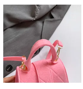 Detail of pink felt handbag showing quilted diagonal texture and gold-tone hardware