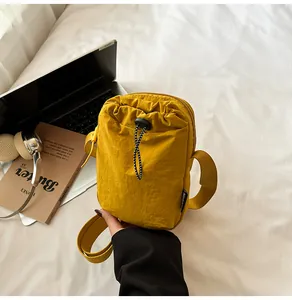 Detail of ginger yellow waterproof nylon crossbody bag with drawstring closure on bed