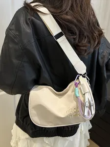 Minimalistische beige halve maan tas met borduursel en kleurrijke hanger