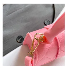 Macro shot of pink felt handbag showing gold metal buckle and quilted diamond stitching