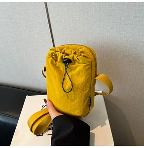 Macro shot of waterproof yellow nylon crossbody bag featuring drawstring pocket and zipper