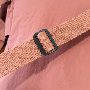 Dettaglio ravvicinato della tracolla in nylon rosa con fibbia di regolazione nera in plastica