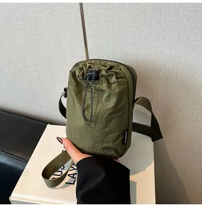 Detail of waterproof olive green nylon crossbody bag with drawstring and fashion label