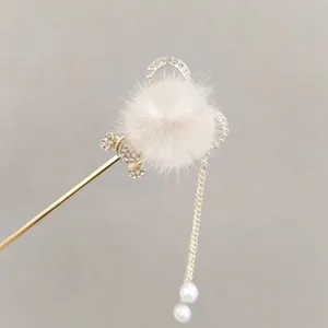 Detail of golden hair pin with white pompom, rhinestones and elegant tassels