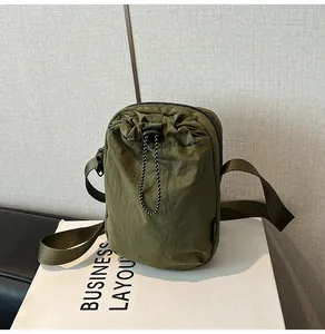 Detail of army green waterproof nylon cross-body bag with drawstring closure and strap