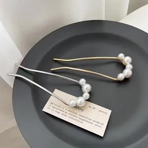 Detail of gold and silver U-shaped hairpins with graduated pearls on a black tray