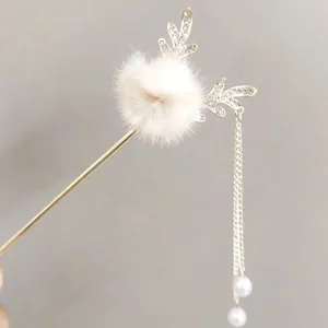 Detailed close-up of winter hair pin with white pompom, rhinestone antlers and long tassels