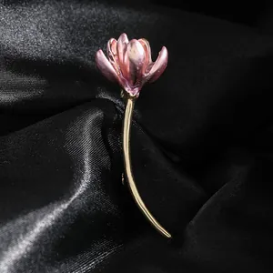 Elegant lotus flower brooch with pink petals and gold stem on black silk background