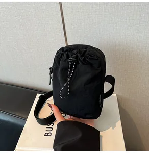 Close-up of waterproof black nylon crossbody bag with drawstring pocket and metal zipper