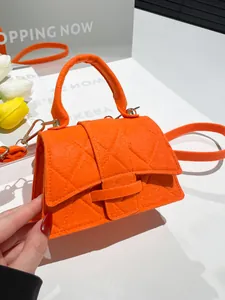 Chic orange felt crossbody bag with quilted pattern and round top handle on white surface