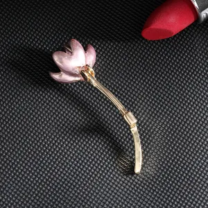 Elegant lotus flower brooch with pink enamel petals and gold stem on black background