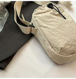 Detail of beige waterproof nylon crossbody bag with drawstring closure and wide strap