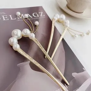 Detail of golden U-shaped hairpins with pearls, tassels and floral engravings
