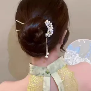 Elegant U-shaped gold hairpin with pearls and tassels shown in a classic updo