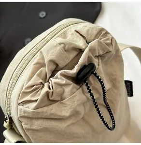 Close-up of beige waterproof nylon crossbody bag with drawstring and fashion label