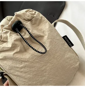 Detail of waterproof beige nylon bag showing drawstring closure and fashion woven label