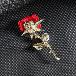 Elegant red rose brooch with gold metal back and pearl detail on textured grey background