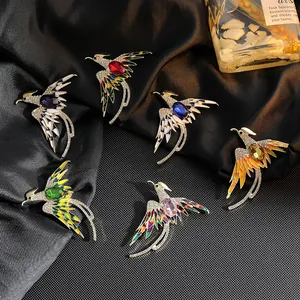 Elegantes broches de fénix con alas de esmalte y piedras ovaladas sobre seda negra fina